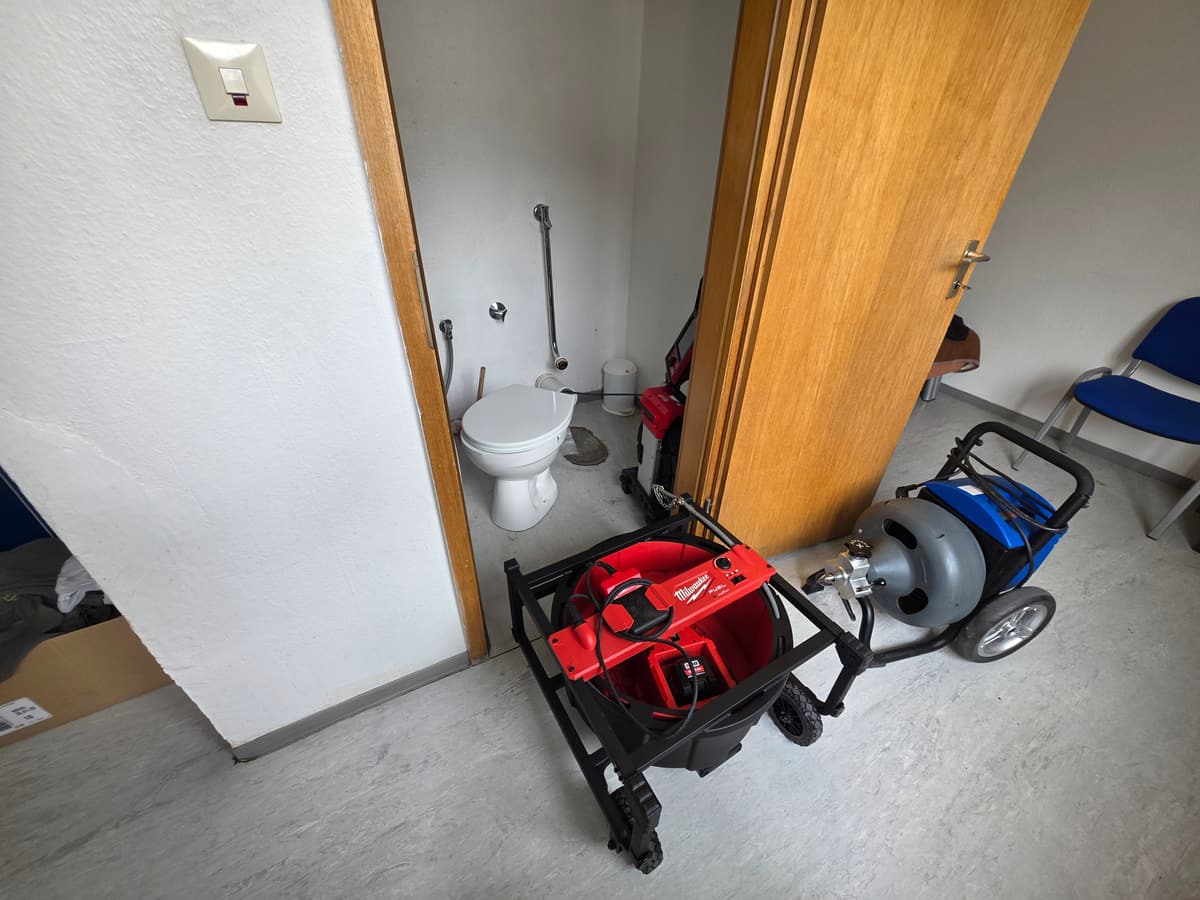 Zwei Rohrreinigungsmaschinen vor einem WC-Raum