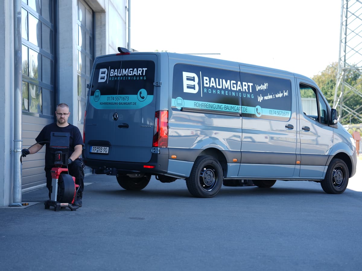 Monteur mit Kanalkamera vor dem Servicefahrzeug von Rohrreinigung Baumgart